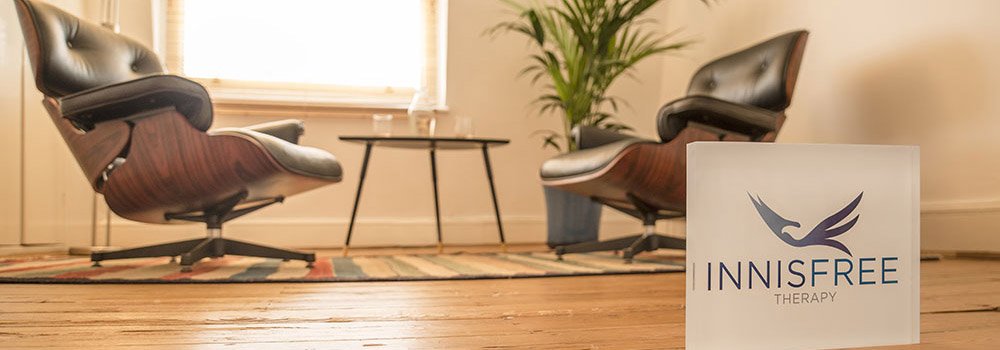 Two comfortable chairs next to a table in a warm and bright therapy room.