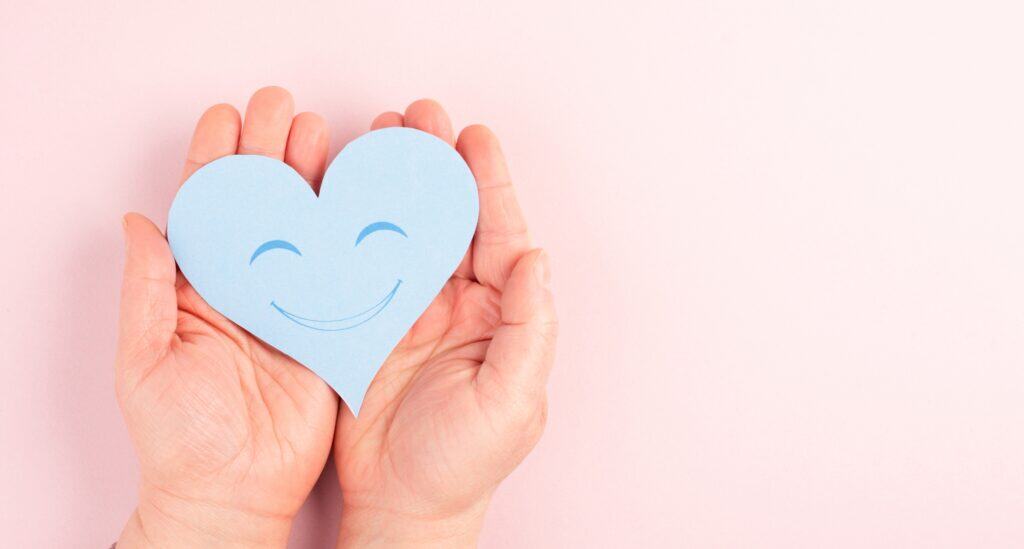 Holding a heart cutout with a smiling face