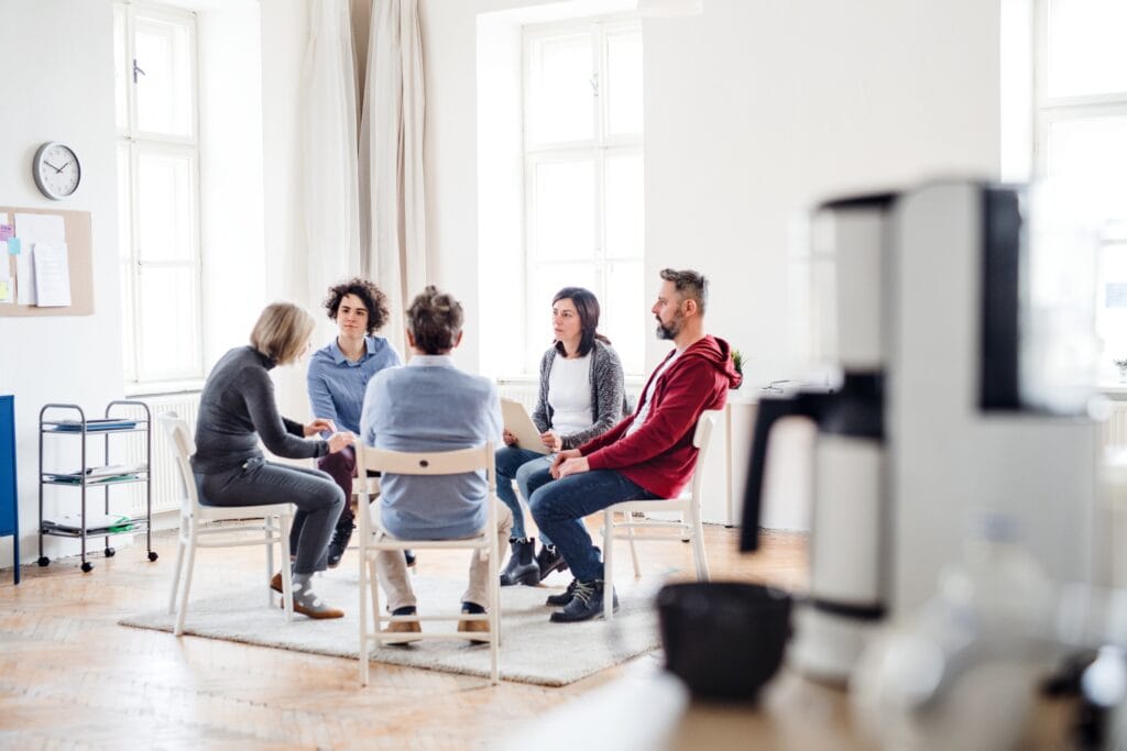 Men and women sitting in a circle during group therapy, concept of workshops and therapy