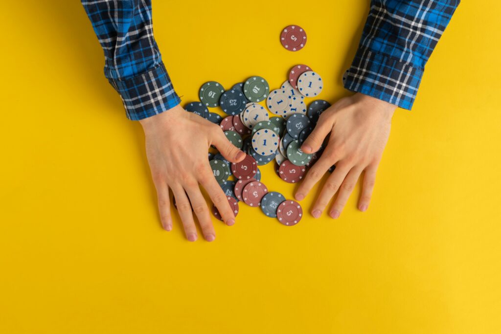shot from above, view of players hands getting gaming chips, concept of gambling addiction