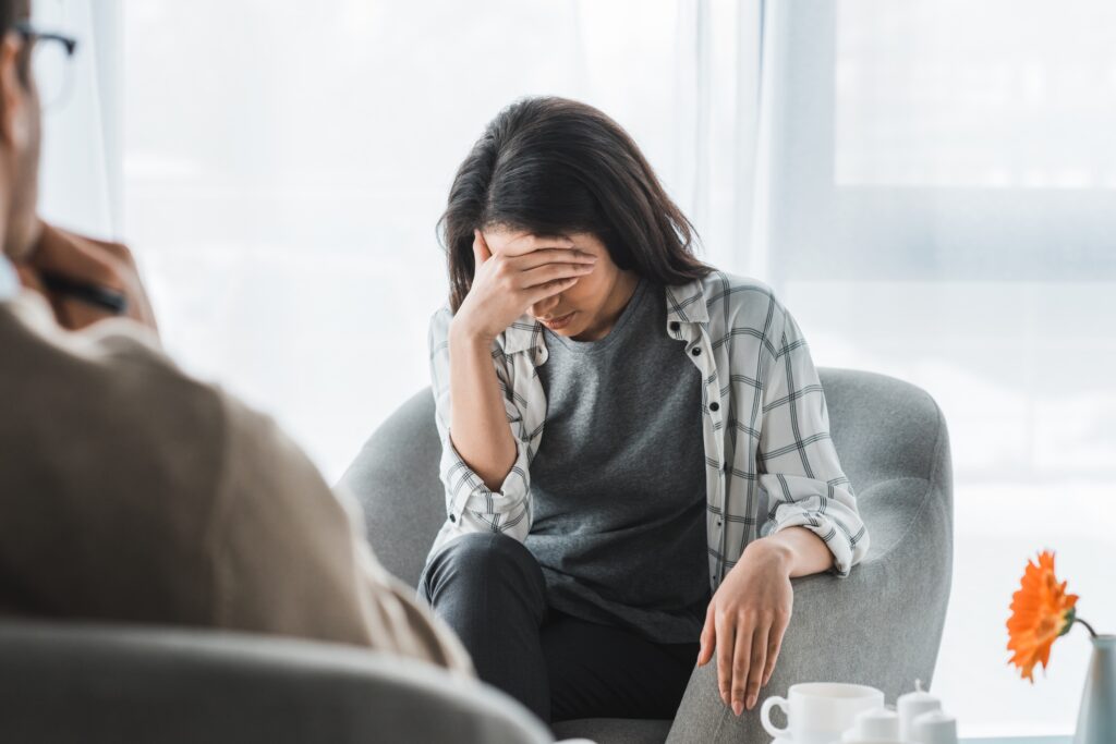 upset woman covering her face during counseling and therapy session