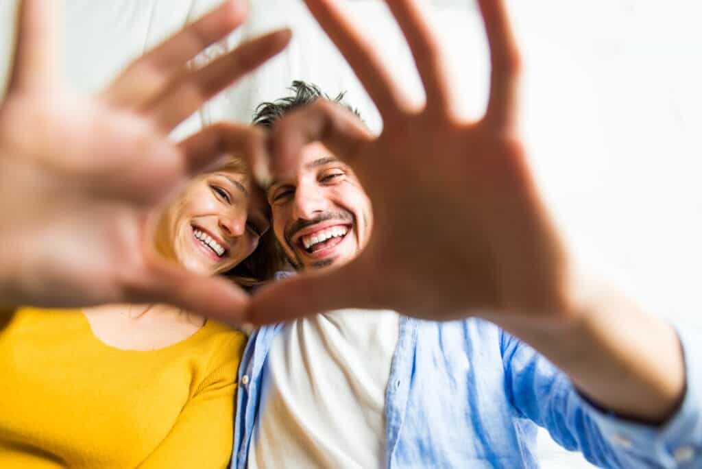 young couple making finger hearts, concept of happy relationship