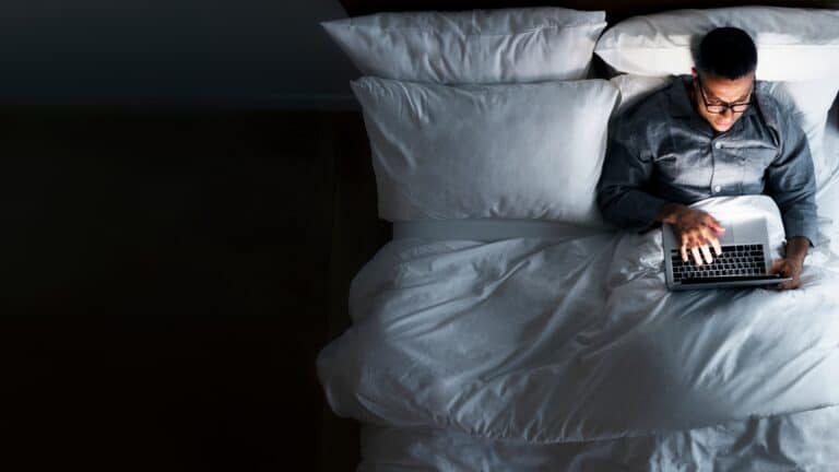 man using laptop while on bed